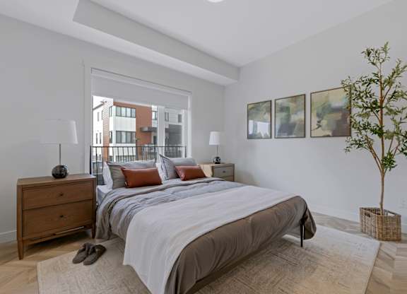 A bedroom with a large bed, a nightstand, and a plant.