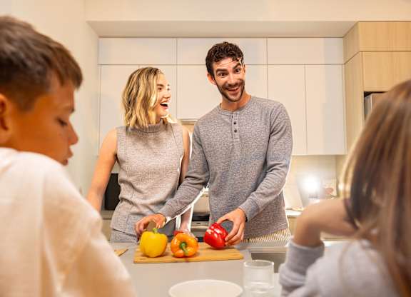 A family of four is preparing food together in the kitchen.
