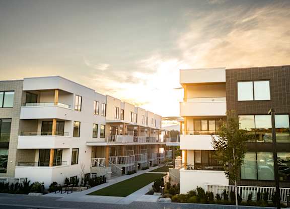 A modern apartment complex with a sunset in the background.