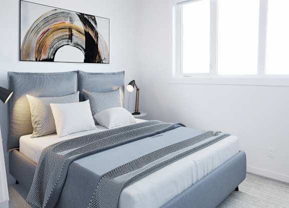 A bed with a grey comforter and pillows is in a room with a large painting on the wall.