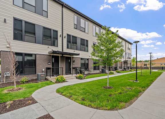 A modern apartment complex with a walkway and landscaping.