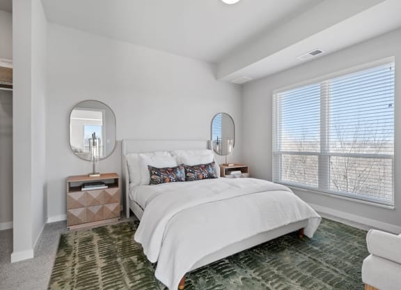 a white bedroom with a large window and a bed