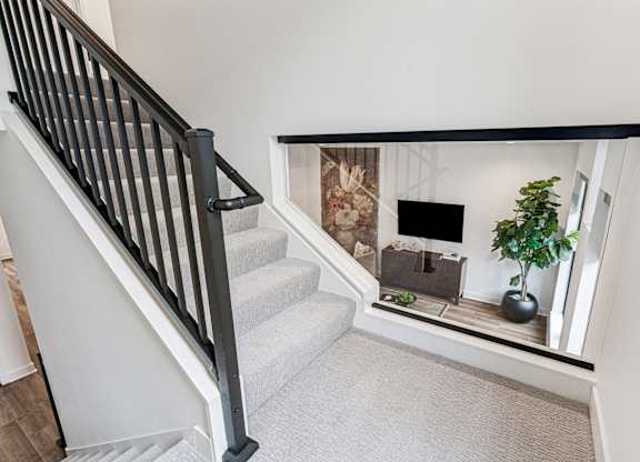 A staircase with a carpeted floor and a black railing.