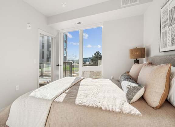 A bedroom with a large bed and a view of the outdoors through a sliding glass door.