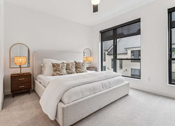 A bedroom with a large bed and two lamps on side tables.