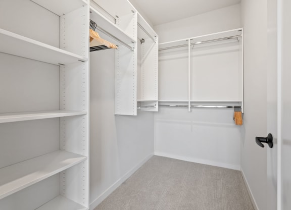 a walk in closet with white shelves and a white closet door