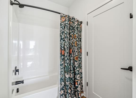 A white bathroom with a floral shower curtain.