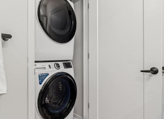 A white door is open to a laundry room with a washer and dryer.
