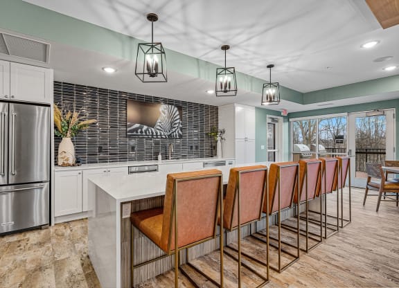 a kitchen with a long counter and chairs and a refrigerator