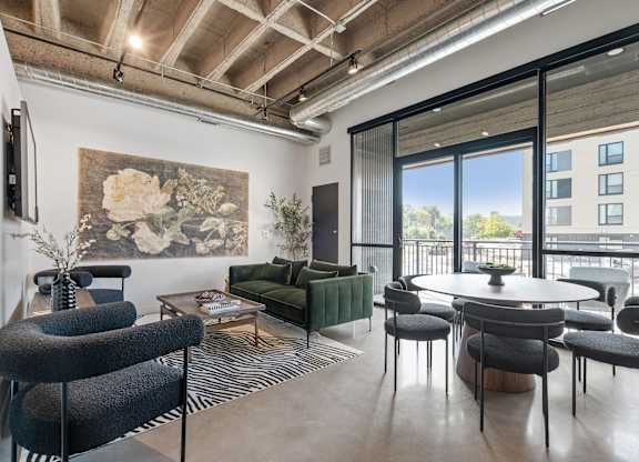 A living room with a large painting on the wall and a view of a balcony.