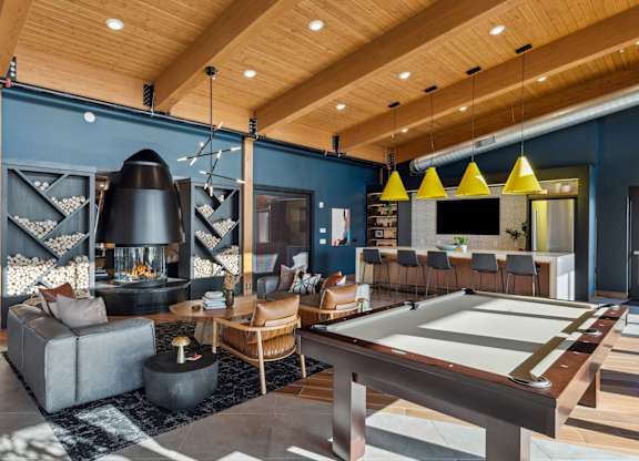 A billiard table is in the middle of a room with a fireplace and a couch.