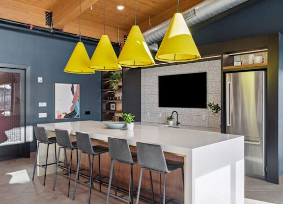 A modern kitchen with a white countertop and grey bar stools.