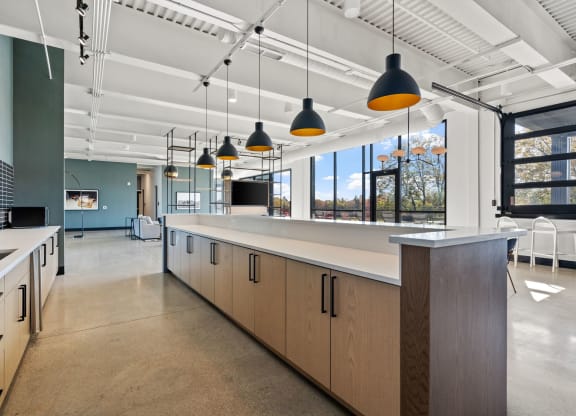 a large kitchen with a long counter and a row of hanging lights