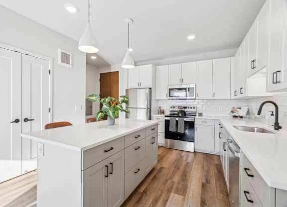 A modern kitchen with white cabinets and a wooden floor.