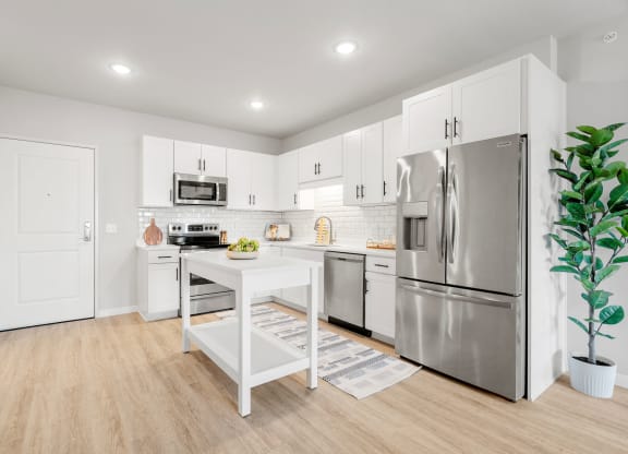 a white kitchen with stainless steel appliances and a white table