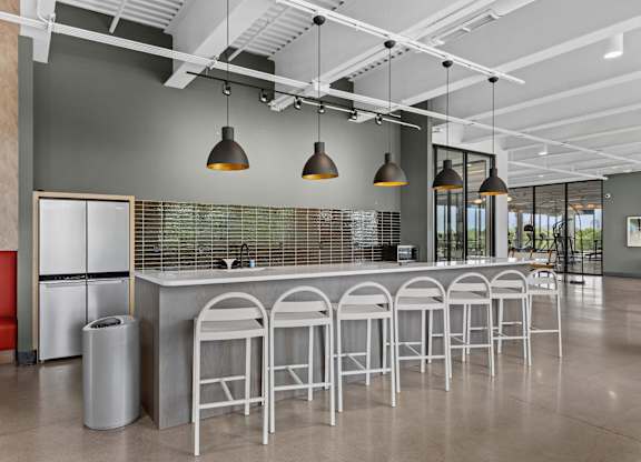 A modern bar area with white stools and a grey counter.