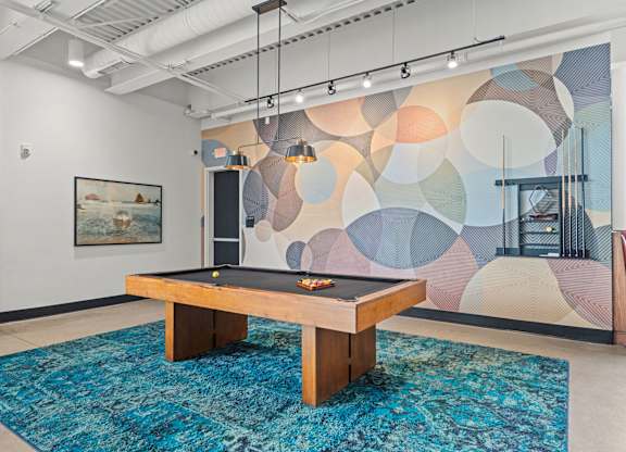 A pool table in a room with a colorful mural on the wall.