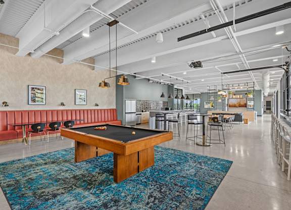 A room with a pool table and a bar area.
