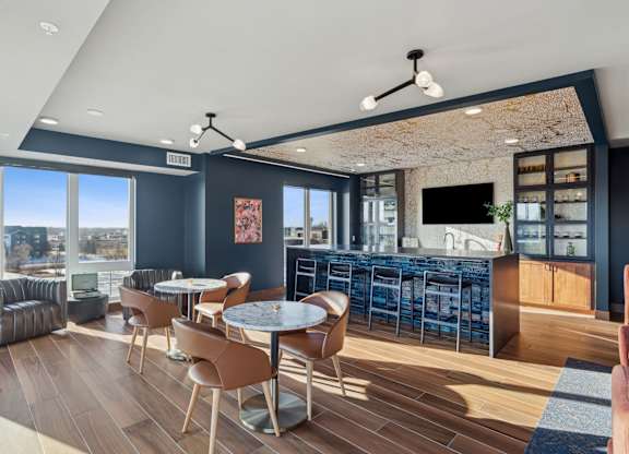 A modern living room with a bar area and a view of the city.