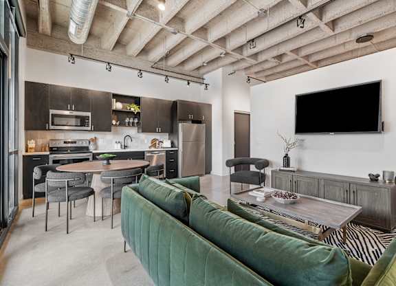 A modern kitchen and living room with a green sofa.