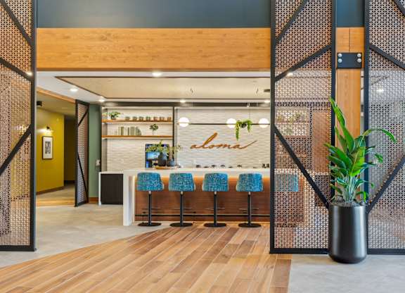 A modern interior with a wooden bar and blue bar stools.