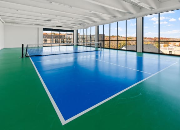 a large indoor tennis court in a building with large windows