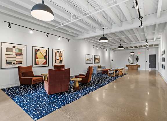 A spacious room with a blue carpet and brown chairs.