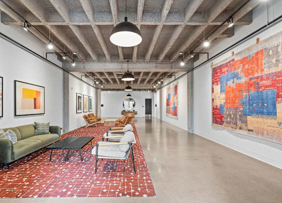 A large room with a long table and chairs and a large painting on the wall.
