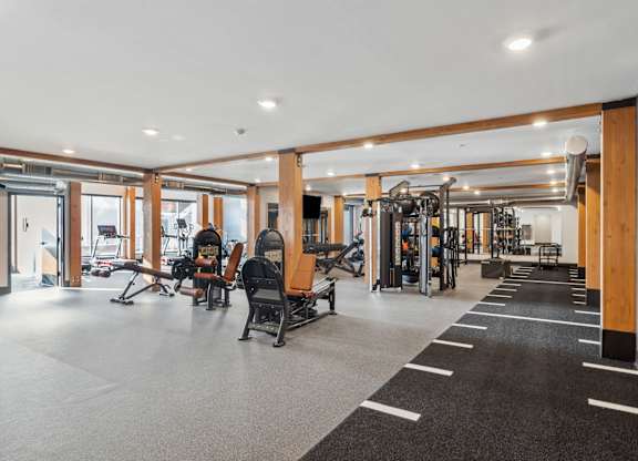 A gym with a variety of equipment including treadmills, weights, and exercise machines.