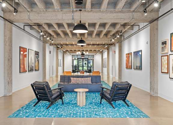 A room with a blue rug and chairs.