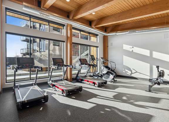 A gym with treadmills, elliptical machines and other exercise equipment.