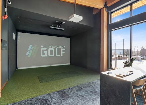 A room with a green carpet and a screen displaying "All Seasons GOLF".