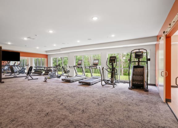 a gym with exercise equipment on the floor and large windows