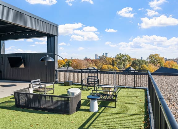 a patio with tables and chairs on a roof with a view of the city