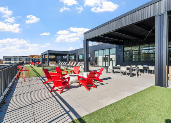 a patio with red chairs and tables outside of a building