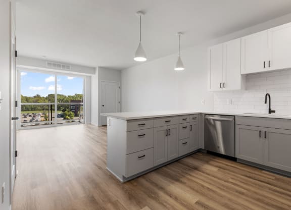 an open kitchen and living room with white cabinets and a sliding glass door