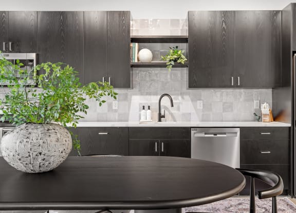a kitchen with black cabinetry and a table with a potted plant