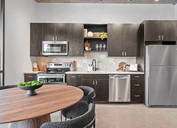 A modern kitchen with a wooden table and black chairs.