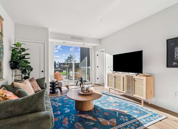 A living room with a couch, a coffee table, and a flat screen TV.