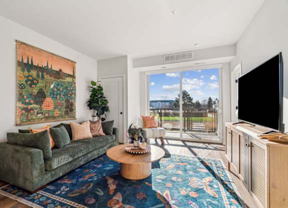 A living room with a green couch and a large painting on the wall.