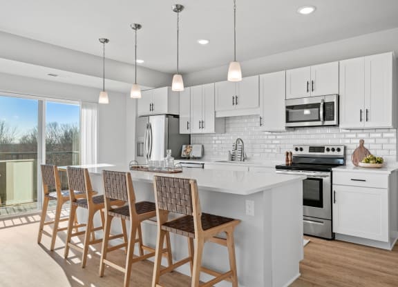 a kitchen with white cabinets and a white island with chairs