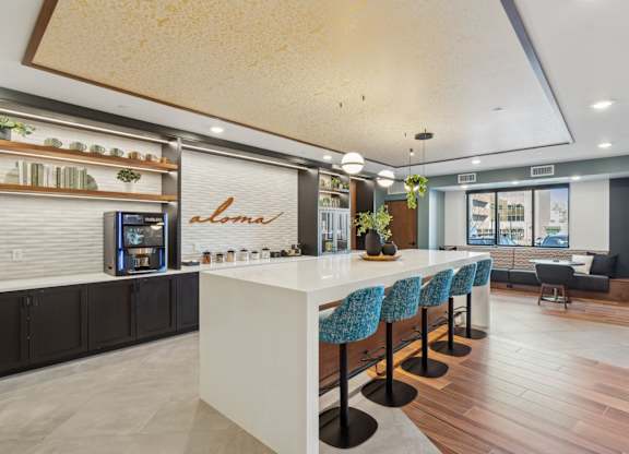 A modern kitchen with a white counter and blue chairs.