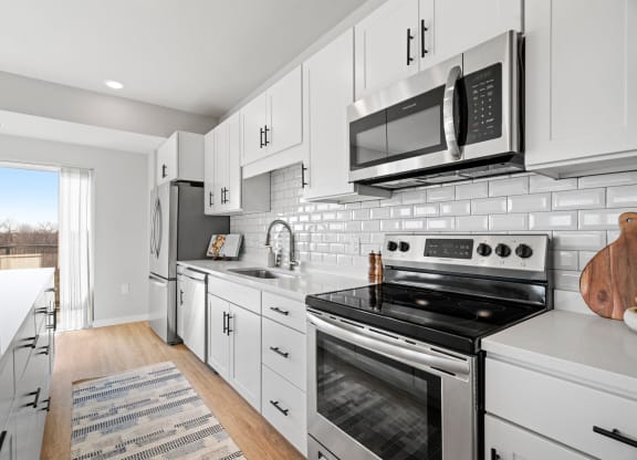 a white kitchen with stainless steel appliances and a microwave