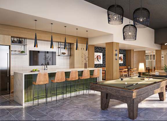 A billiard table is in the middle of a room with a bar and a television.