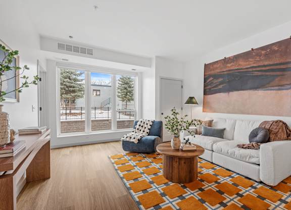 A living room with a white couch, a coffee table, and a large painting on the wall.