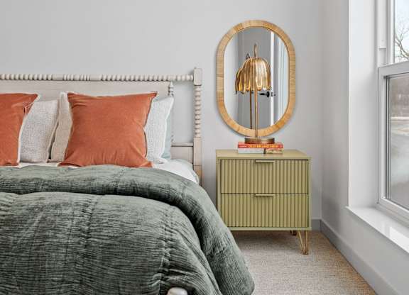 A bedroom with a bed, a dresser, and a mirror.