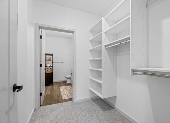 A white hallway with a doorway leading to a bathroom.