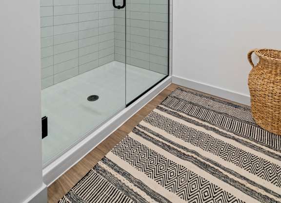 A bathroom with a glass shower door and a wicker basket on the floor.