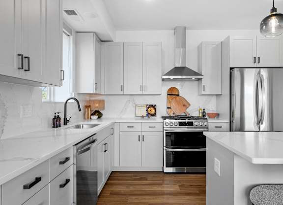 A modern kitchen with white cabinets and stainless steel appliances.