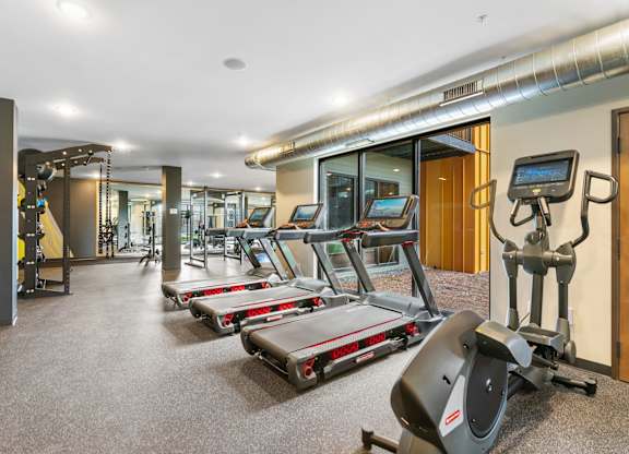 A gym with treadmills, elliptical machines, and other exercise equipment.